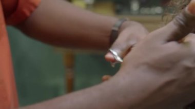 Kuaförde saç kesimi yaparken seyreltici makas kullanan siyah erkek berberin ellerini yakın plan çek.