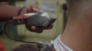 Berber ellerinin, müşterinin boynuna saç kesme makinesi ve fırçayla saç keserken çekilen gayri resmi.