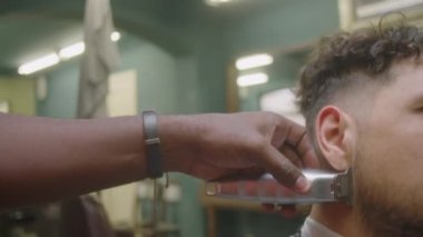 Erkek müşterinin sakal yakasını tıraş ederken tıraş bıçağı kullanırken kesilmiş bir berber fotoğrafı.