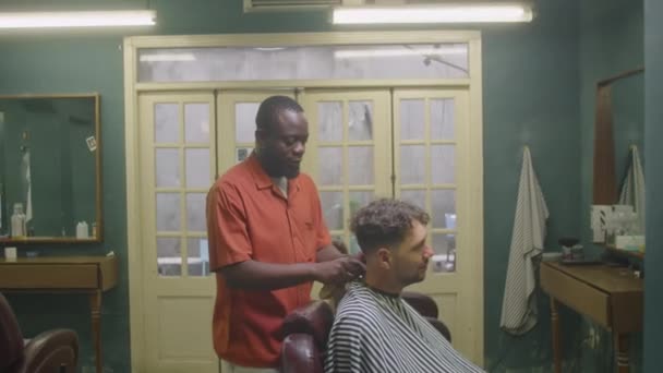 Счастливый Человек Встает Стула Парикмахерской После Стрижки Благодарит Афроамериканского Парикмахера — стоковое видео
