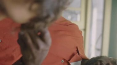 Berber dükkanında çalışırken Afrikalı Amerikalı berberin saç makası kullanırken ve müşteriyle konuşurken dikey pozu.