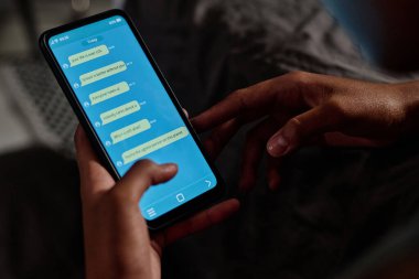Siber zorbalık içeren anonim mesajlarla depresif Afrikalı Amerikalı genç kızın elinde tuttuğu akıllı telefon ekranı.