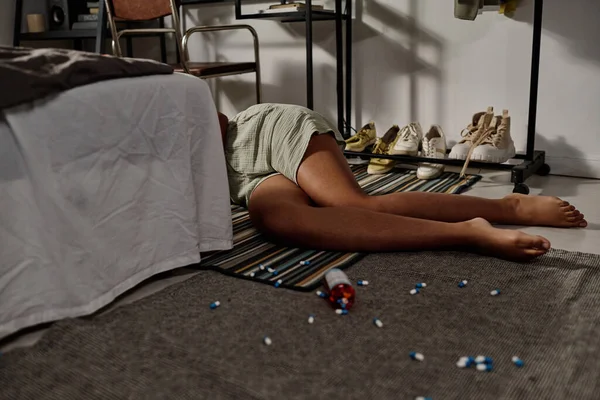 Siber zorbalıktan sonra intihar ederken çift kişilik yatağın arkasında dağınık haplarla yerde yatan Afro-Amerikalı genç kızların bacakları.