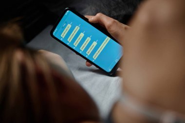 Yatakta yatan stresli genç kız tarafından tutulan agresif ve saldırgan siber zorbalık mesajları içeren akıllı telefon ekranına odaklan.