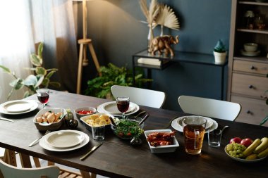 Ev yapımı meyve suyu, limonata, kırmızı şarap, kızarmış tavuk, sebze salatası ve taze meyvelerden oluşan ahşap masa.