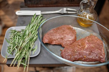 Salamura edilmiş etin yüksek açılı görüntüsü ızgarada otlar ve yağla pişirmeye hazırlanıyor.