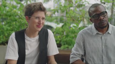 Afro-Amerikalı işadamı ve beyaz iş kadını açık hava takım toplantısı sırasında iş arkadaşlarıyla konuşuyor.