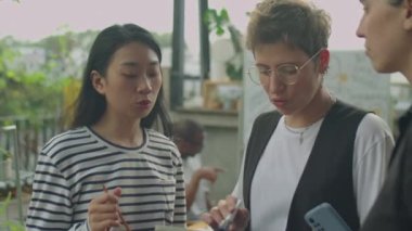 Açık terasta çalışırken dijital tablet üzerinde iş planlarını tartışan bir grup genç bayan meslektaşın orta ölçekli görüntüsü.