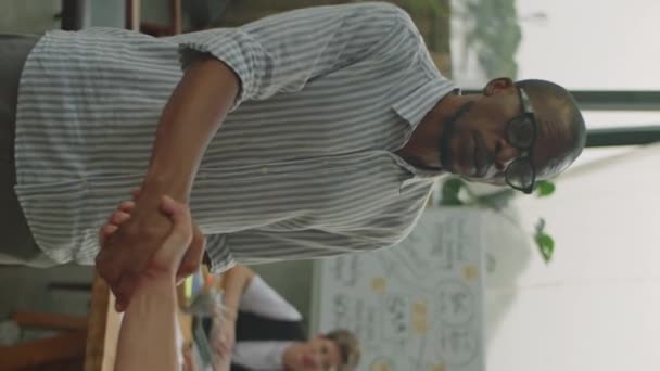 アフリカ系アメリカ人の実業家が握手をして 屋外テラスで同僚と話す垂直ショット — ストック動画