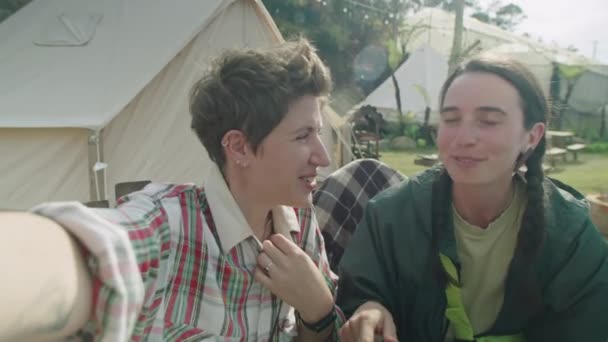 两个快乐的女游客坐在户外 一边微笑着 一边在摄像机前聊天 一边在山顶放暑假 — 图库视频影像