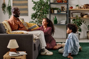 Neşeli bir oğul ve kız babasından Afrika Amerikan tarihi kitabı okumasını istiyor.