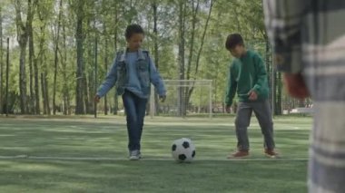 Küçük Afrikalı Amerikalı ve Asyalı çocukların futbol topunu tekmeleyip gol attıkları ve arkadaşlarıyla parkta oynarken heyecanlandığı uzun bir çekim.