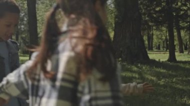 Çemberde dans eden ve yaz günü parkta eğlenen çok ırklı çocukların yavaş çekimleri.