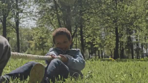 Menino Feliz Sentado Grama Verde Puxando Corda Com Emoção Enquanto — Vídeo de Stock