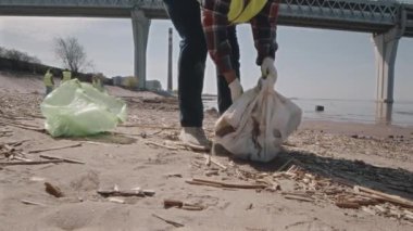 Çevreci gönüllülerin tekstil torbalarını alıp, kum torbasını sallayıp, sonra da sahil şeridini temizlerken çöp torbasına attıkları görüntüler.