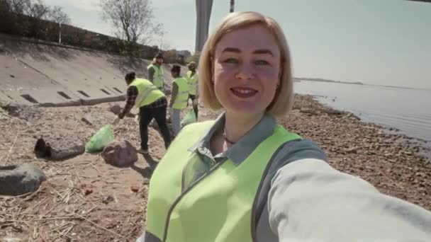 カメラを見ている女性の環境ボランティアのPovショットと 海岸清掃中にビデオ通話やビデオ通話を撮影しながら話す — ストック動画