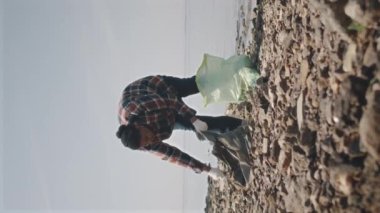 Sahilde çöpleri toplarken eldivenli Afrikalı Amerikalı çevrecilerin dikey çekimi.