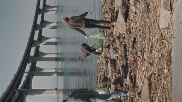 海岸の清掃をしている間ゴミ袋にゴミを集める環境活動家の垂直フルショット — ストック動画