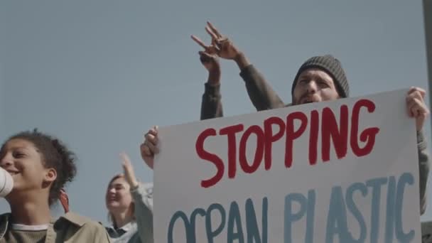 若い多様な環境活動家グループが海洋プラスチックサインを止め 水質汚染に抗議するメガフォンで話す — ストック動画