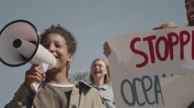 Kirliliği protesto etmek için bir grup çevreci eylemciyle dikilirken megafonla konuşan genç siyah kız