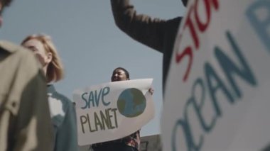 Çevre aktivistleri arasında hava kirliliğini protesto eden Save Planet posteriyle duran genç Afrikalı Amerikalı kadın