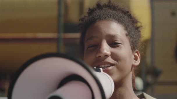 Młoda Czarna Dziewczyna Stojąca Zewnątrz Patrząca Kamerę Mówiąca Megafonem Podczas — Wideo stockowe