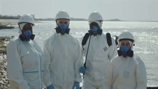 保護カバー ヘルメット 呼吸マスクのプロの生態学者のグループ肖像画は 汚染された地域の海岸線上のカメラのために一緒にポーズ — ストック動画