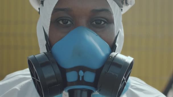 保護カバーオールの黒人女性エコロジストの肖像画 ガスパイプラインに対する屋外のカメラのためのハードハットと呼吸マスク — ストック動画