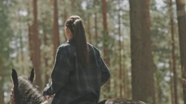 Arka planda yaz günü ata binen çiftlerin yavaş çekim görüntüleri var.