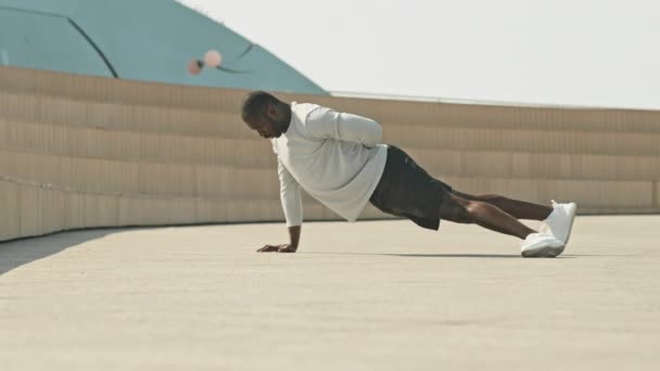 アフリカ系アメリカ人スポーツマンが午前中の都市公共スペースでアウトドアを行っている間 ワンアームプッシュアップ — ストック動画