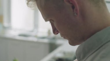 Genç adamın mutfak masasının yanında, elinde alışveriş malzemeleri ve marketten gelen okuma makbuzuyla görüntülerini yakın çekim yapın.