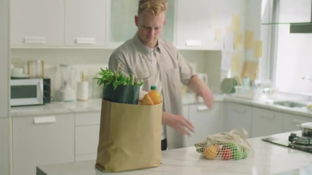 Młody Człowiek Przynosi Torbę Papierową Stołu Kuchennego Domu Rozładowuje Zakupy — Wideo stockowe