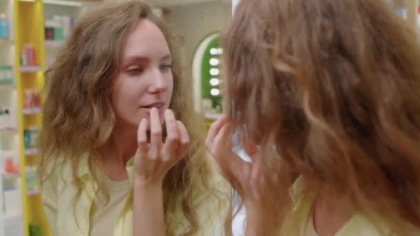 Kozmetik Mağazasından Alışveriş Yaparken Dudaklarına Merhem Sürerken Aynanın Yanında Duran — Stok video