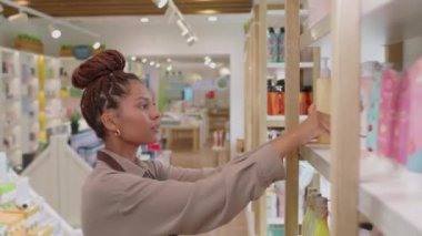 Kozmetik mağazasında çalışırken kameraya bakan neşeli genç satış elemanı portresi