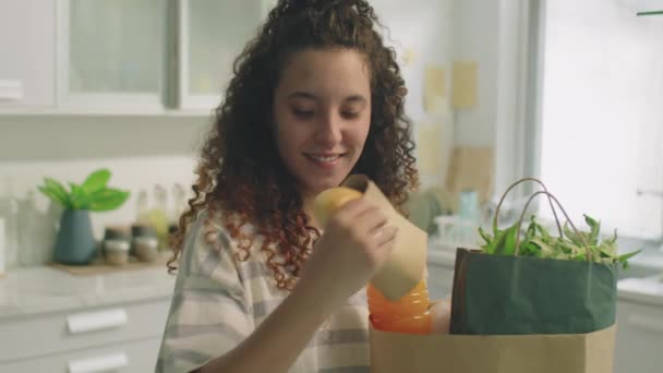 Mladá Usměvavá Dívka Kudrnatými Vlasy Sundavat Potraviny Nákupních Tašek Kuchyni — Stock video