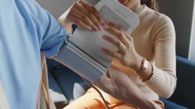 Sağlık görevlisinin yaşlı kadınların kollarına kelepçe takıp evdeki kan basıncını ölçtüğü görüntüler.