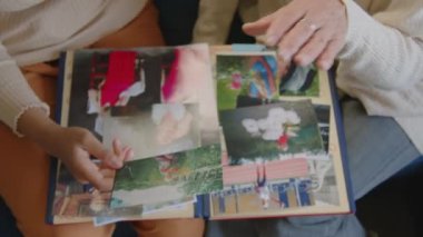 Genç kadın ve yaşlı büyükannenin evdeki kanepede oturup aile fotoğraflarının albümünü izlerken çekilmiş üst çekimleri kapat.