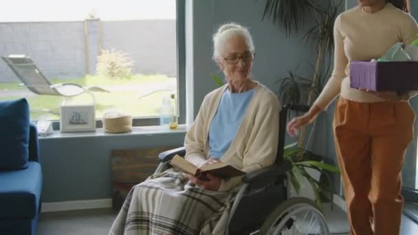 Kobieta Asystentka Pielęgniarstwa Spaceru Materiałów Czyszczących Rozmawiać Starszą Kobietą Wózku — Wideo stockowe