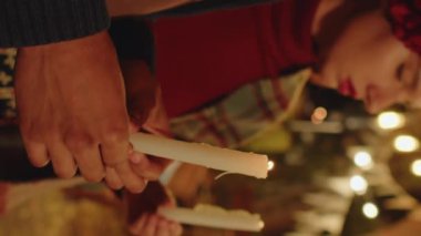 Genç Latin çiftin dikey kesilmiş görüntüleri ellerinde mumlarla sunak başında gece rahat arka bahçede Dia de Muertos 'u kutluyorlar.