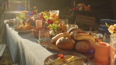 Güneşli bir günde, sonbaharın arka bahçesinde vazolarda taze ekmek, mum ve kadife çiçekleri bulunan güzel yemek masasının ışıklarını kimse göremez.