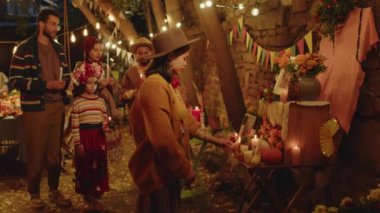 Modern Latin ailenin güzel dekore edilmiş sunaklarına doğru giderken çekilmiş orta boy bir fotoğrafı ve Ölüler Günü 'nde vefat eden aile üyelerinin anısına mum yakıyor.