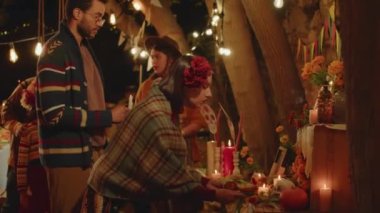 Orta boy Latin bir kadının, sıcacık arka bahçedeki güzel dekore edilmiş sunağa ölü ekmek koyduğu bir resim. Meksikalı aile, Ölüler Günü 'nü kutluyor.