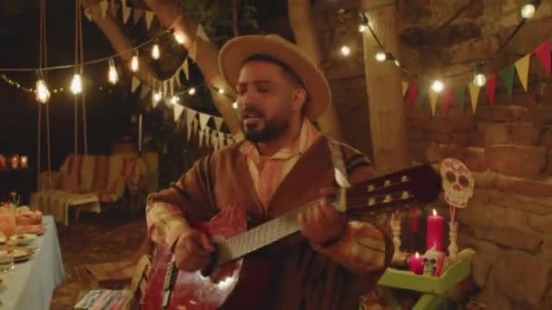 ドリーは 陽気なヒスパニック系の友人や家族が夜の裏庭で一緒に死者の日を祝いながら一緒に踊ったり楽しんだりしたショットを撮影しました ギターを弾いている男性の一人 — ストック動画