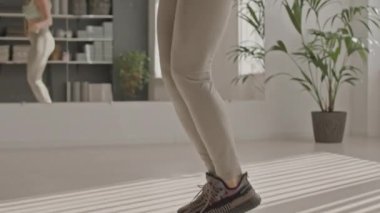 Spor kıyafetli, spor kıyafetli, atlama halatıyla spor salonunda antrenman yapan olgun, zayıf bir kadının fotoğrafını çek.