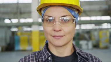Fabrikada durmuş kendine güvenen güvenlik gözlüklü kadın sanayi işçisinin portresi.