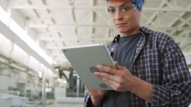İş sırasında dijital tablet kullanan üniformalı kadın fabrika müfettişinin görüntüsü.