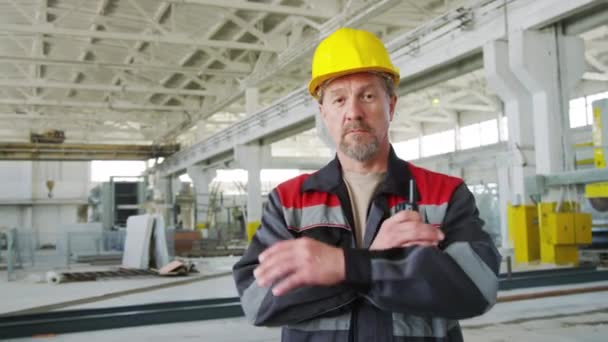 工业厂房的成年男工程师头戴硬礼帽 身穿工作服 双臂交叉地站着 手持对讲机 摆姿势拍照的画像 — 图库视频影像