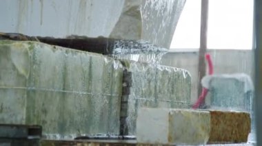 Gündüz vakti taş kesme fabrikasında yıkanan doğal mermer bloklarının üzerinden akan temiz suyun yavaş çekim görüntüsünü yukarı kaldır.