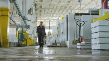 İş kıyafetleri içinde orta yaşlı bir adamın gün boyu taş fabrikasında yürürken çekilmiş fotoğrafı.