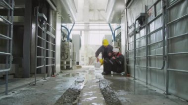 Kadın işçilerin ilk yardım çantasını alıp, bandajlı kafası olan yaralı erkek meslektaşlarının endüstriyel fabrikada geçirdikleri kazadan sonra ayağa kalkıp yürümelerine yardım ettiği geniş bir çekim.